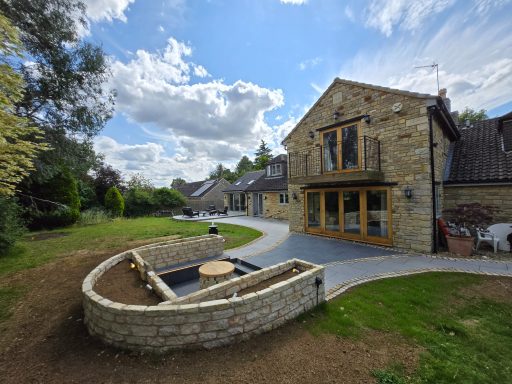 A sunken firepit area featuring natural stone walling and porcelain patio