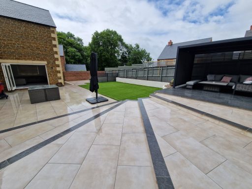 A large porcelain patio area with step feature, artificial grass and decking area